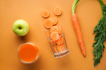 Flat lay composition with fresh carrot juice, apple and fresh carrots on a brown background. Close-up.