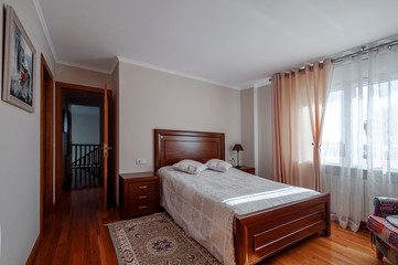 Interior of cozy bedroom in modern design with wooden floor and bed.