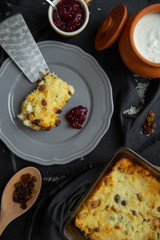 Cottage cheese casserole with raisins on a gray plate, poured sour cream on top. Flat lay, view from above. 
