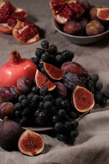 Fruit plate: figs, black grapes, plums, pomegranate. The concept of a healthy diet and a healthy lifestyle. Selective focus
