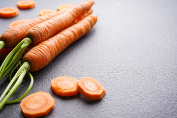 Close-up composition with ripe fresh carrots on a grey background, with space for text