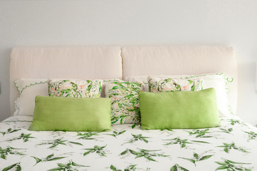 Soft headboard with green pillows.