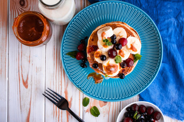 Delicious and lush pancakes with fresh fruits and berries, poured with salted caramel.