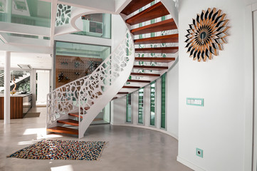 Beautiful white spiral staircase with wooden steps and white iron railings. Selective Focus Photo