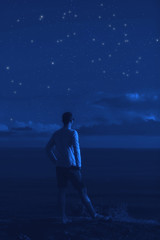 Fototapeta premium Silhouette of a man with milky way stars above the ocean horizon.