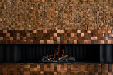 Modern and luxury fireplace built into the wall with brown wooden coating. Close up and copy space.