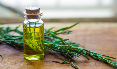  top view of rosemary essential oil on a rustic wooden background. Herbal oil concept