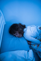 Small 11 year old girl sleeping in bed on a stomach.