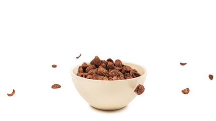 Chocolate corn flakes falling to the white bowl isolated on white. Motion.