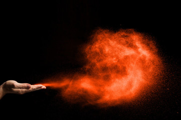dust blows from hands on black background. color Lush Lava