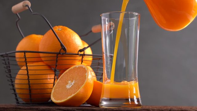 Fresh orange juice pouring into tall glass .