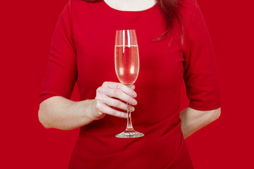 close up of a woman dressed in red holding a flute of bubbles prosecco champagne aperitif festivity party elegance on red background
