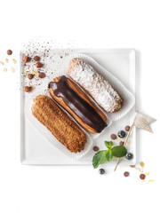 food photography of assorted eclair cakes with different fillings (chocolate, icing sugar, caramel) on a white background isolated top view
