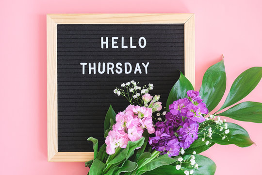 Hello Thursday text on black letter board and bouquet colorful flowers on pink background. Concept Happy Thursday. Template for postcard, greeting card Flat lay Top view