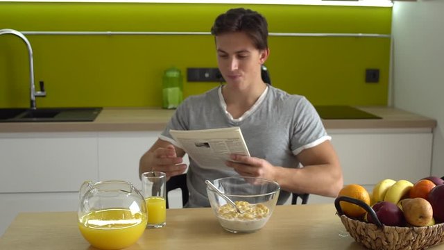 Young man in the kitchen daily routine concept having breakfast reading news