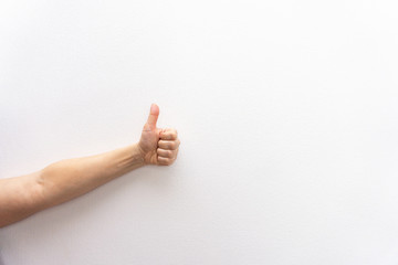 Left hand of white caucasian woman or girl makes thumb up gesture, approves or agrees, white background, body language concept. copyspace.