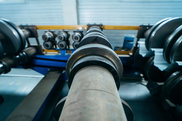Fototapeta na wymiar Close up industrial steel roll coil for metal profile forming machine in metalwork factory workshop. Metal rolls, concept for metalwork 