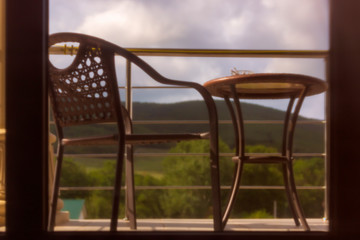 Place to relax with wicker chair on hotel open balcony, view from behind curtain