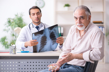 Fototapeta na wymiar Young male doctor and old patient in antismoking concept