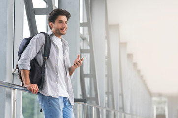 Waiting For Flight. Man Traveller Relaxing In Airport Terminal With Smartphone