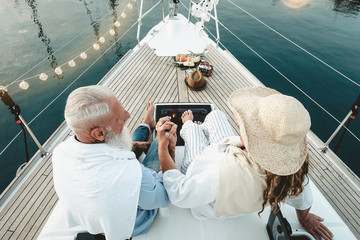 Senior couple celebrating wedding anniversary on sailboat - Happy mature people having fun on boat...