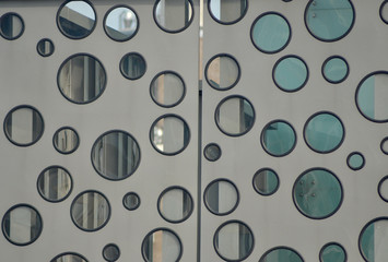 A random patterm of glass circles (similar to portholes) on a door. The door is grey, the circles framed in black. An industrial scene can be glimpsed through the glass