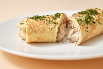 Close-up rolled pancake with filling from chicken and mushroom.