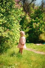 Obraz premium little girl lilac bushes. Spring blooming gardens.
