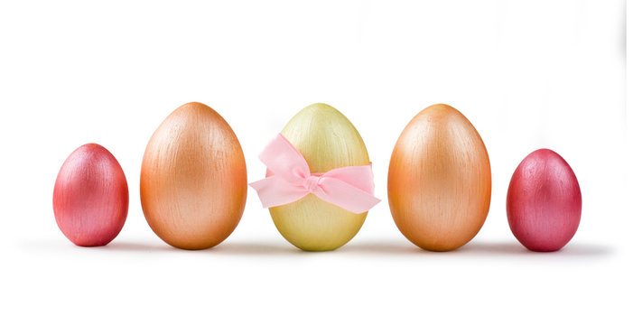 Cute golden and pink metallic Easter eggs with bow isolated on white.