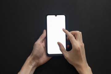 Smartphone in hands with the screen on on a black background zooms in with two fingers.