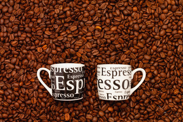Two Cups of coffee on a table full of coffee beans.