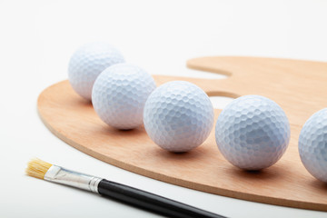 Clean wooden art palette with white golf ball and one brush