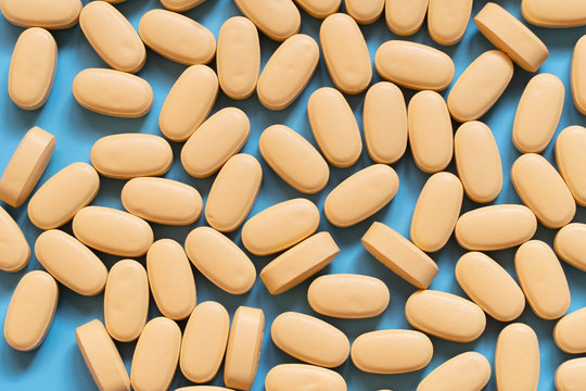 Pile Of Yellow Medicine Tablets On Blue Background. Lopinavir/Ritonavir Combination Tablets For The Treatment And Prevention Of HIV/AIDS. Top View.