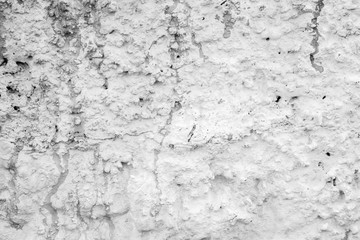 Close-up of a rough and plastered stucco wall painted in white. Drips and stains of paint. High resolution full frame textured background in black and white.