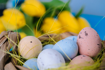Happy Easter. Easter holiday decorations on trendy colored classic blue background. Creative spring composition with Easter elements - flowers and eggs in basket. Celebrating Easter concept at spring.
