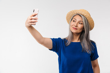 Image of adult mature woman wearing straw summer hat using cellphone