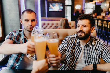 Old friends meeting. Three cheerful young men drinking beer in pub