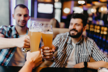 people, men, leisure, friendship and celebration concept - happy male friends drinking beer and clinking glasses at pub