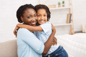 Black mother and daughter hugging at home