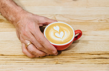 Cup of freshly brewed cappuccino with tulip latte art served on wooden table, close-up view