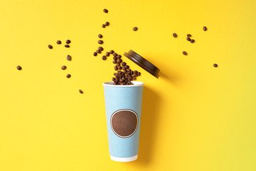Take away coffee cup and coffee beans on yellow background. Top view. Copy space. Minimal composition, layout for design. Coffee concept.
