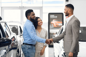 Car Dealer Handshaking With Buyers After Successful Deal In Store