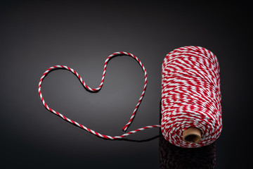 Conceptual image of a roll of rope on a black background, in the shape of a heart.