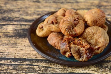 Dried figs in a plate on wooden background