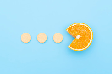 Vitamin C supplements pills with Orange Fruit Cross Section isolated on blue background. Vitamin...