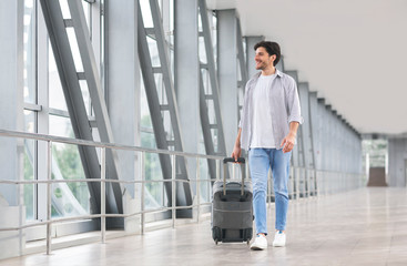 Start Of Journey. Handsome Man With Luggage Walking In Airport Corridor