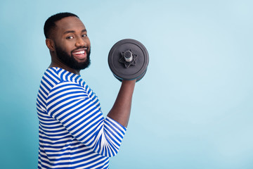 Profile photo of cool funny handsome dark skin guy lifting heavy dumbbell weight practicing hard gym strong man wear striped sailor shirt isolated blue color background