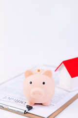 Financial concpet - Piggy bank, beautiful red white wooden house model on white background, saving money to buy insurance, close up, copy space.
