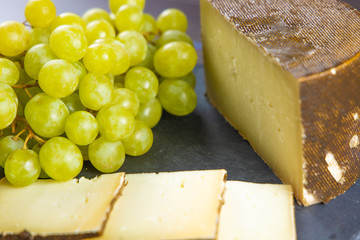 Still life of fresh cheeses of different flavors with fresh grapes ready to eat