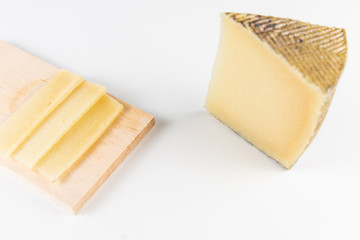 Fresh cheeses of different flavors with nuts on black chalkboard plate and wooden board on white...